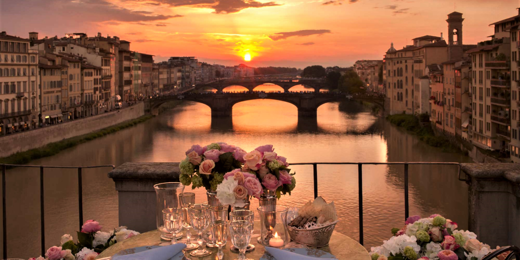 Picture of a dining table in front of a river at sunset